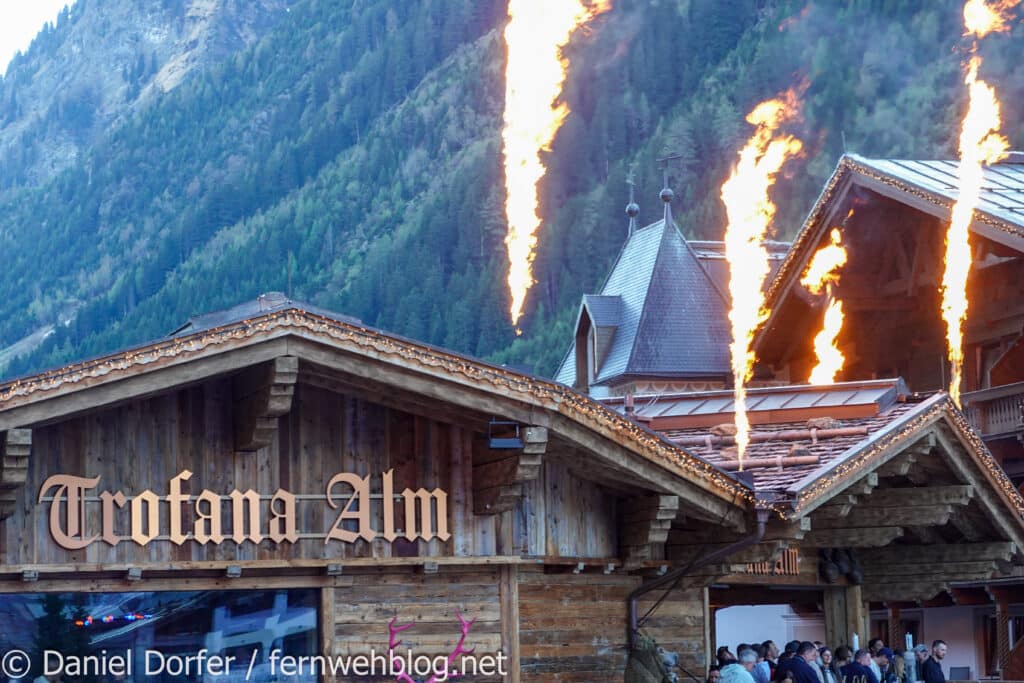 Trofana Alm in Ischgl mit Pyrotechnik-Flammensäulen über dem Dach vor Bergkulisse beim Saisonfinale 2026