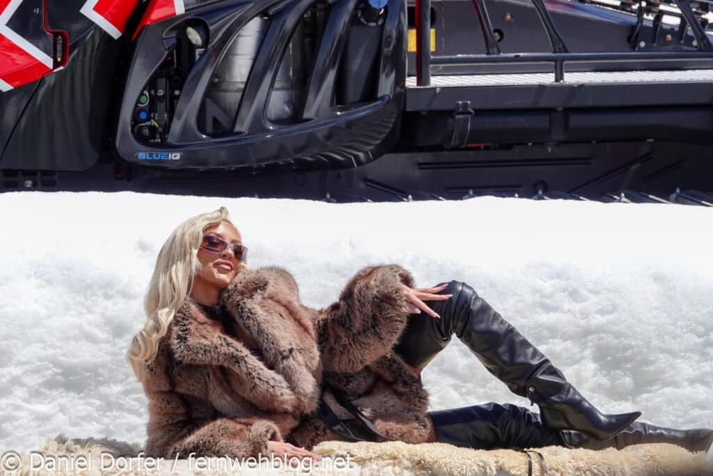 Christina Aguilera in Pelzmantel und Lederstiefeln auf einem Schaffell vor der Pistenraupe beim Pic in the Snow Ischgl 2026