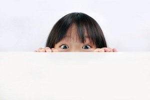 child peaking over edge of table