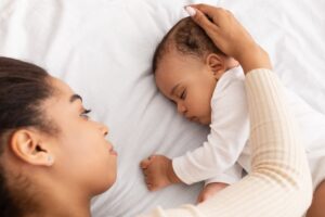 napping baby with mother by -Prostock-Studio iStock-1312608327-min napping infant with mother