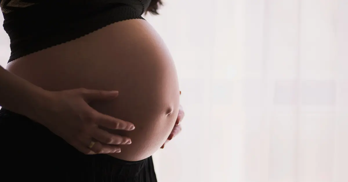 A pregnant person holds their belly