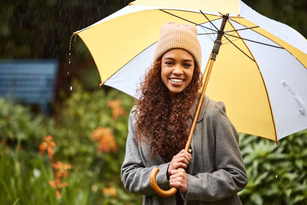 woman smiling holding up an umbrella with curly hair in humidity