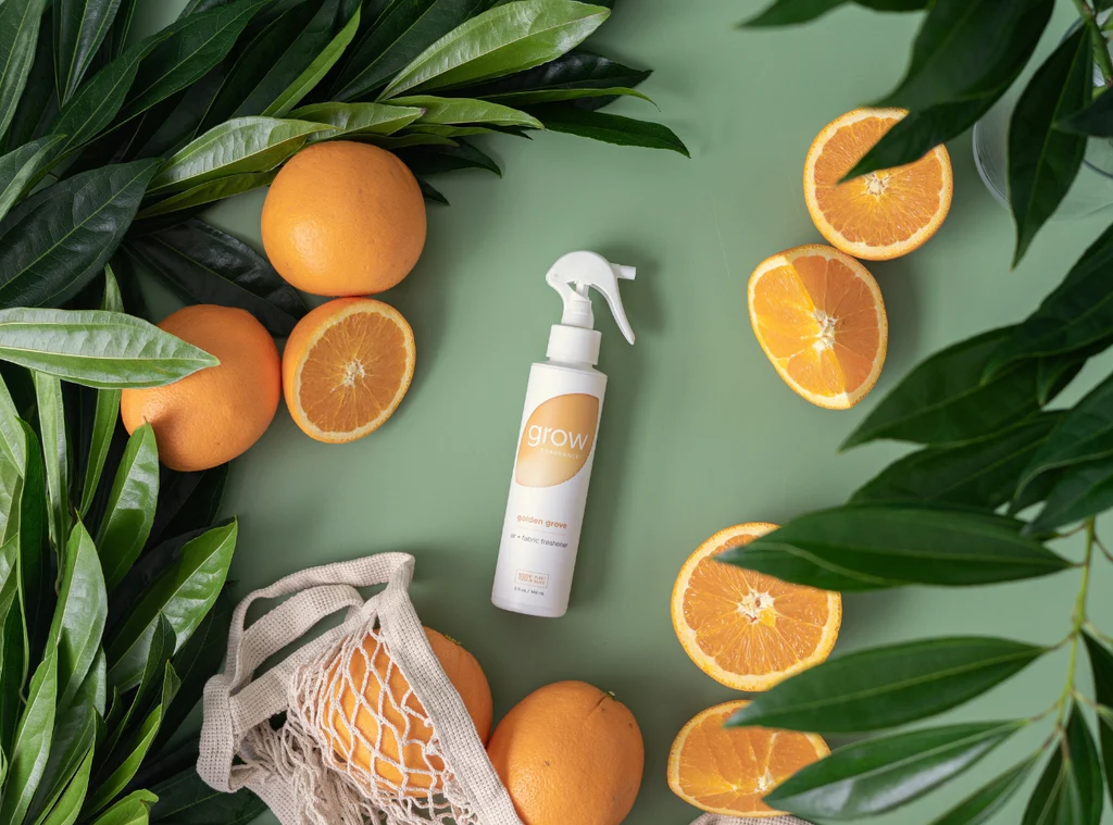 Golden Grove Air + Fabric Spray on green backdrop surrounded citrus slices and greenery (featured)