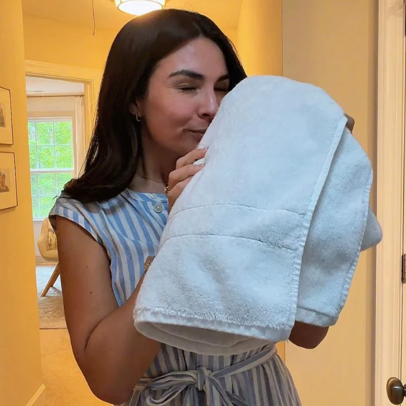 Woman holding a light blue towel in a room with yellow walls.