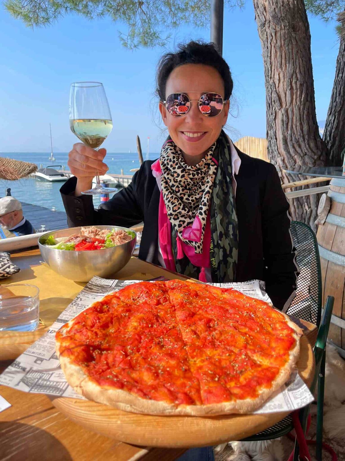 Moderatorin Mary Amiri genießt Essen und Wein am See im Sonnenschein