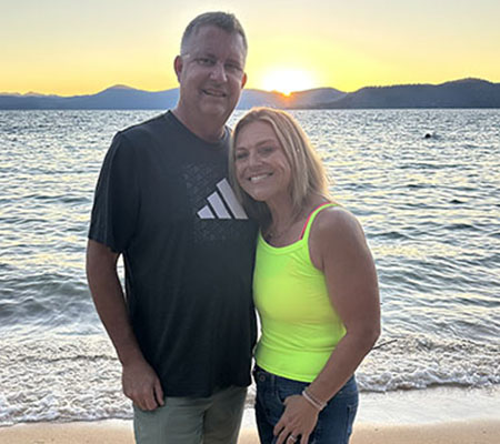 Ein Mann und eine Frau umarmen sich bei Sonnenuntergang am Strand. 